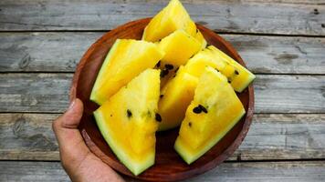 Yellow watermelon slices on wooden plate and isolated on gray board background. Healthy food, vegan. Antioxidant photo