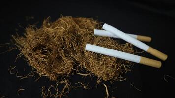 dry cut tobacco leaf, cigarettes and cigarette machine on black background. handmade cigarettes photo