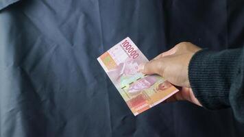 Asian young woman in black coat transacting rupiah with men only the hands, transaction concept, financial concept. asian man holding rupiah banknotes, isolated on black and white background. photo