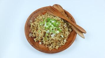 Nasi Goreng - Indonesian Chicken Fried Rice on wooden plate isolated on white. Nasi Goreng is an Indonesian cuisine dish with jasmine rice, chicken meat, onion, egg, vegetables. Indonesian Food. photo