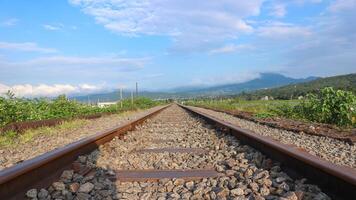 Railroad track in sunny clouds. The railway passes through the autumn forest. photo