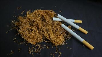 cortar tabaco hojas y hecho a mano cigarrillos en negro antecedentes foto