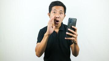 Asian man hold smartphone and whispering some secret gossip isolated on white background. photo
