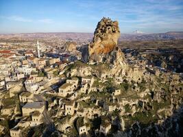 aéreo zumbido ver de el ortahisar castillo en capadocia, Turquía con el nieve tapado montar erciyes en el antecedentes. personas disfrutando el ver desde el parte superior de el castillo. foto