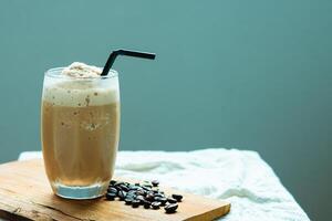 Frappe coffee cup on a glass plate on a wooden with roasted coffee bean copy space for your text photo