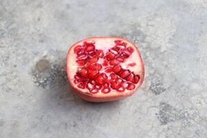 a pomegranate is cut in half on a concrete surface photo