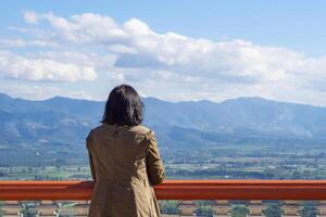 A back view of a middle woman stands alone looking at mountains. Beautiful nature background. Concept of people and relaxation photo