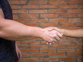 Close-up of shaking hands between man and woman with brick background. Unity Concept. photo