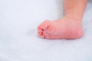 Little foot of newborn baby on a white blanket photo