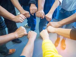 Closeup image of many people putting their fists together as symbol of unity with sunlight effect. photo