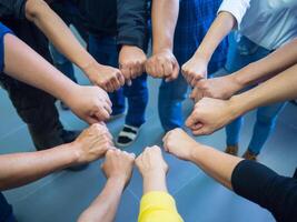 Closeup image of many people putting their fists together as symbol of unity. Teamwork Concept. photo