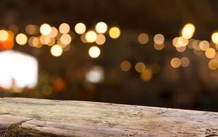 Empty wood table top on blur light gold bokeh of cafe restaurant in dark background photo