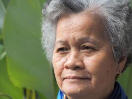 Portrait of beautiful elderly woman smiling and looking at camera while standing in a garden photo