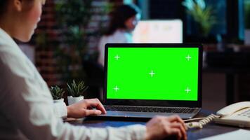 Worker looks over statistical financial data on chroma key laptop, researching data for company project. Businesswoman analyzing stock market figures and charts on mockup device video