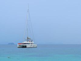 hermoso paisaje marino de superficie azul brillante con yate blanco flotante foto
