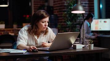 Employee calling manager to her computer desk to ask for feedback on project progress. Worker in office late at night requesting assistance from team leader on tasks done on laptop video