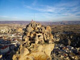Aerial drone view of the Ortahisar Castle in Cappadocia, Turkey with the snow capped Mount Erciyes in the background. photo