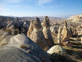 Aerial drone view of a person admiring the natural beauty of Pasabag Valley or Monks Valley and  Fairy Chimneys in Cappadocia, Turkey. Famous destination for hikers to explore the Rock Sites. photo