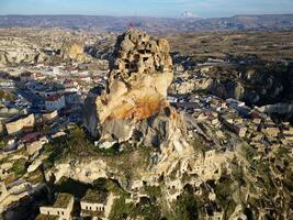 aéreo zumbido ver de el ortahisar castillo en capadocia, Turquía con el nieve tapado montar erciyes en el antecedentes. personas disfrutando el ver desde el parte superior de el castillo. foto