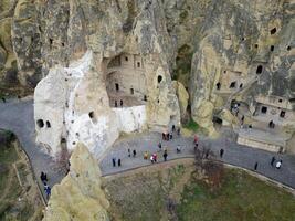 View of the Goreme Open Air Museum in Cappadocia, Turkey. This Unesco World Heritage site is an essential stop on any Cappadocian itinerary. Tourists visiting the historical site. photo