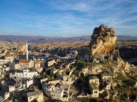 Aerial drone view of the Ortahisar Castle in Cappadocia, Turkey with the snow capped Mount Erciyes in the background. People enjoying the view from the top of the castle. photo