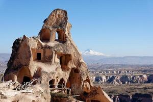 View of an old troglodyte settlement in Uchisar with Mount Erciyes in the background. Travel concept for Cappadocia. photo