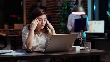 Tired employee struggling to remain focused at workspace desk, feeling overworked and waiting to go home. Bored businesswoman sighing in office while working overnight, camera B video