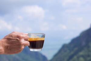 Close-up of a man hand holding a coffee cup with beautiful scenery view of mountains. Morning coffee feeling happy and freedom photo