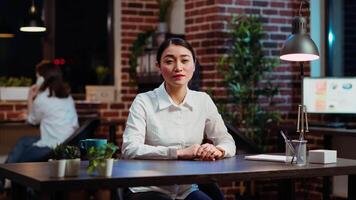 POV of smiling asian worker greeting colleagues during business meeting on videocall in office. Portrait of friendly employee participating in remote videoconference telework call video