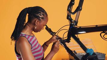 Afrikaanse Amerikaans ingenieur toepassingen schroevedraaier naar ontkoppelen fiets stuur, testen componenten kwaliteit in studio achtergrond reparatie winkel. professioneel losschroeven fiets onderdelen in bestellen naar fix hen, camera een video