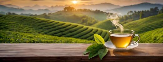 AI Generated A steaming cup of tea with green leaves on a wooden surface with a scenic tea plantation at sunrise. Panorama with copy space. Banner. photo