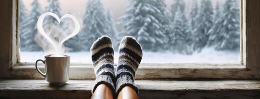 AI Generated Cozy feet in wool socks by a windowsill, with a steaming cup and a heart-shaped steam above, overlooking a snowy forest. Panorama with copy space. White background. photo