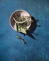 Sage and thyme in a bowl with a blue background photo