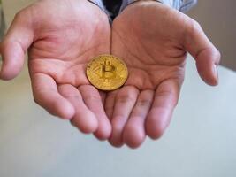 Close-up of bitcoin coin placed on hands young man photo