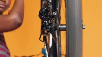 Close up shot of bike wheel being tested by woman doing servicing in studio background atelier shop. Technician fixing bicycle tires, checking for faults in break rotor and chain video