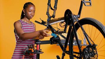 ingeniero con tableta en mano analizando dañado bicicleta terminado estudio antecedentes esperando reparar y mantenimiento. mujer utilizando electrónico dispositivo a diagnosticar bicicleta en reparar pararse, cámara si video