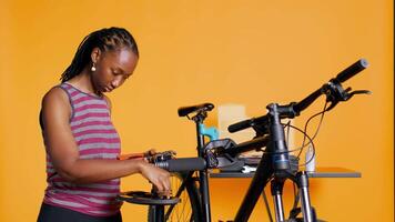 Afrikaanse Amerikaans monteur voorbereidingen treffen werk gereedschap voordat beginnend repareren gebroken cliënt fiets, studio achtergrond. professioneel regelen van mechanisch apparatuur, klaar naar begin vaststelling fiets, camera b video