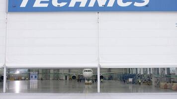 Roller shutter door and concrete floor of airport hangar and airplane background. Airport hangar from the outside with big tall doors video