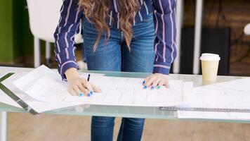 Close up hands of female architect drawing on blueprints for new development project. video