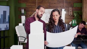 Team of architects holding blueprints with building models in the office. Building concept. video