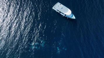 Motor boat in blue ocean and bubbles by divers on water surface. Aerial view video