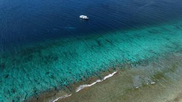 Motor boat in blue tropical sea near reef wall on Maldives. Aerial view video