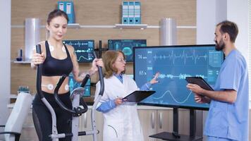scienziato nel sport industria controllo il cardio di femmina atele. femmina atleta in esecuzione con elettrodi allegato per sua corpo video