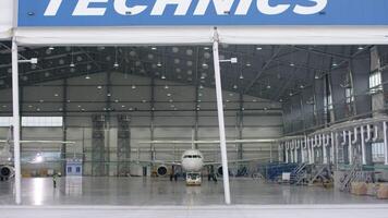 Roller shutter door and concrete floor of airport hangar and airplane background. Airport hangar from the outside with big tall doors. Front view. Aircraft Hangar video