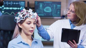 Female doctor in neuroscience using a futuristic device to read brain activity from her patient. Eeg. video