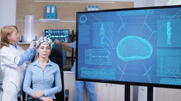 tv schermo con cervello attività a partire dal femmina indossare cervello scanner. femmina paziente con onde cerebrali lettura teste. video