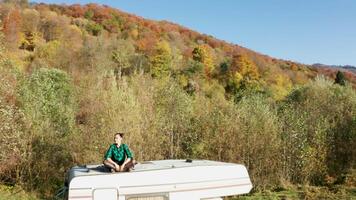 Drone footage of beautiful young woman admiring the scenary from the top of retro camper van. Girl camping. video