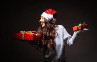 un festivo mujer con presenta un mujer en un Papa Noel sombrero participación dos regalos foto