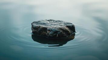 ai generado un solitario rock flotadores tranquilamente encima ondulación agua, sus reflexión reflejando tranquilidad, ai generado foto