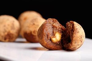 Beautiful candy truffle with a nut inside on a white plate on a black background photo